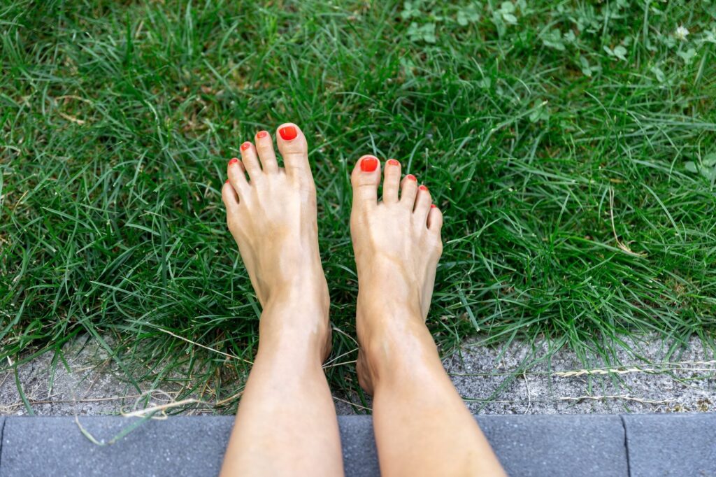 Nackte Füße mit gespreizten Zehen im Gras