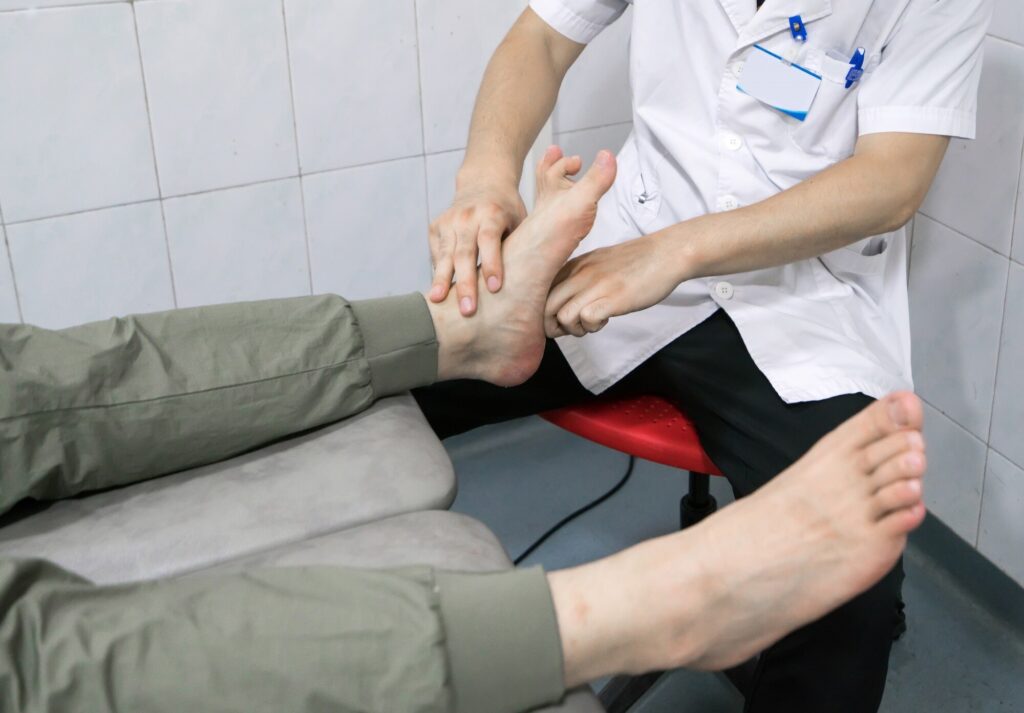 Eine Therapeutin untersucht den nackten Fuß einer Patientin