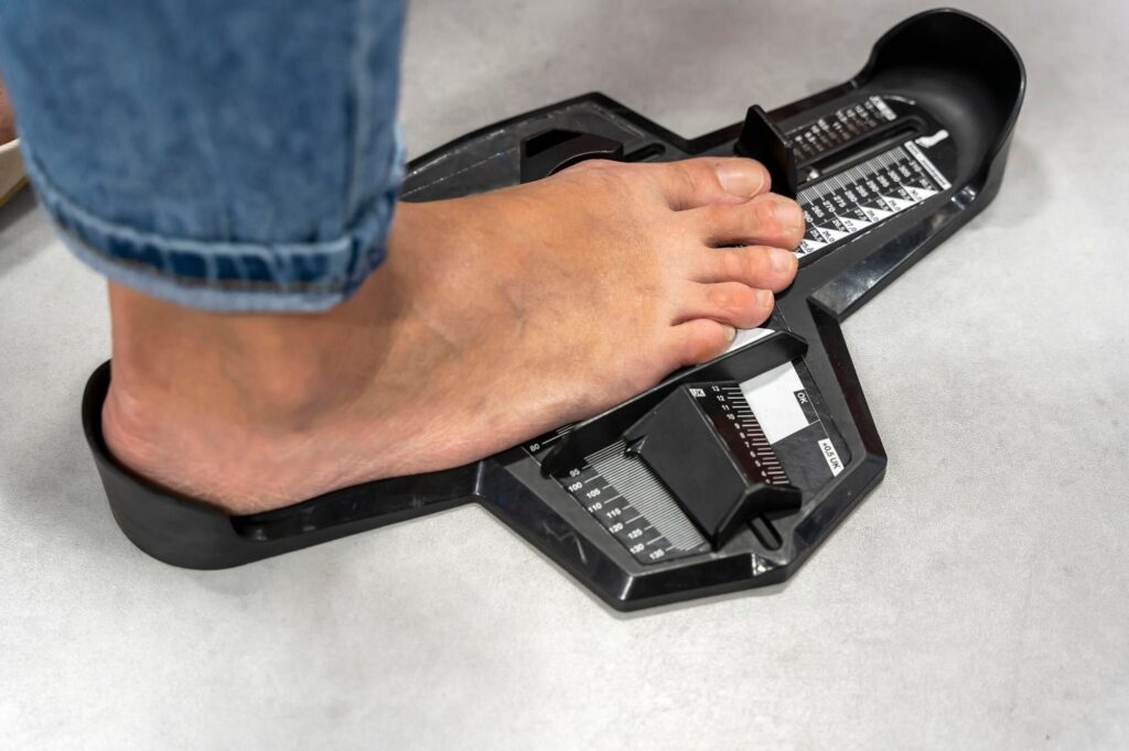 Ein nackter Fuß steht auf einem Fußmessgerät im Schuhgeschäft