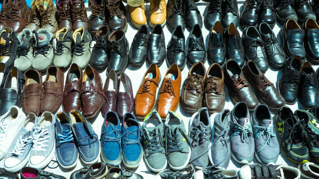 Draufsicht: Dutzende gebrauchte Schuhe in Reihen, nach Farben sortiert