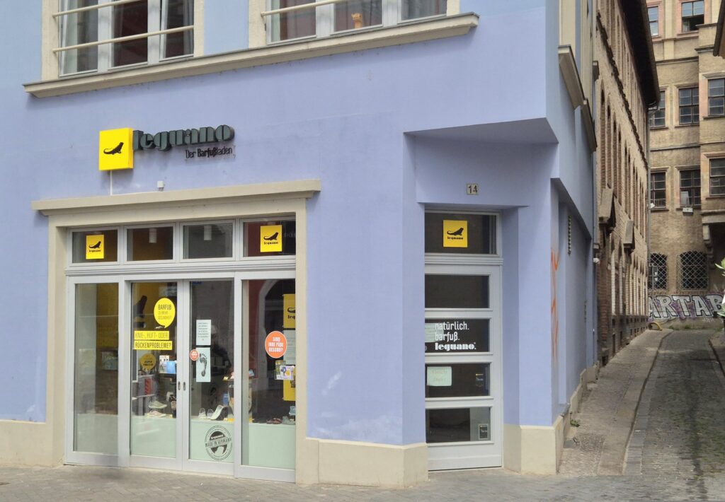 Fliederfarbenes Eckhaus in Halle mit Leguano-Schriftzug über dem Eingang, rechts eine Gasse