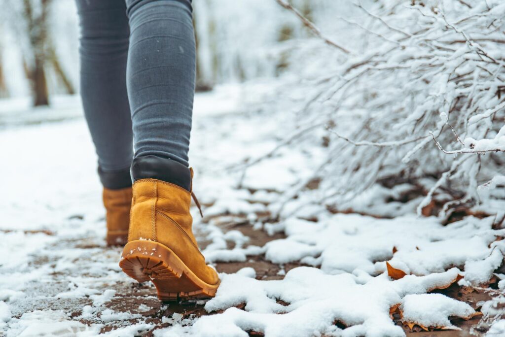 Gelbe Winterstiefel gehen über einen verschneiten Weg